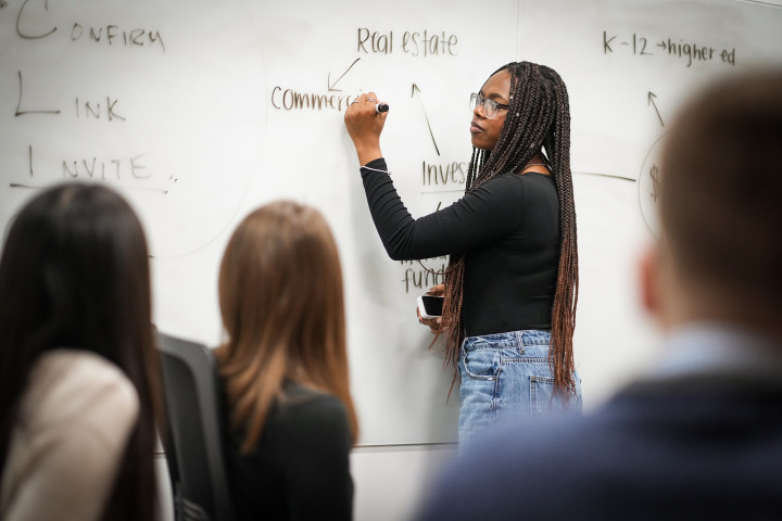 Students in the classroom, with a student working at the white board.