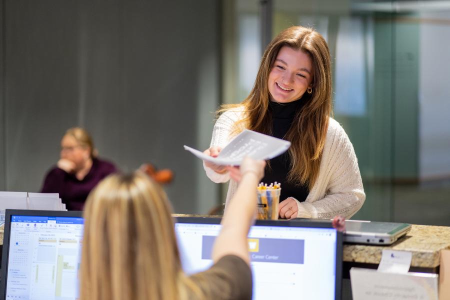 a student handing over paperwork.
