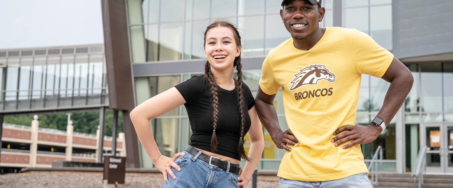 Admissions leaders smiling, on main campus outside near the fountains.