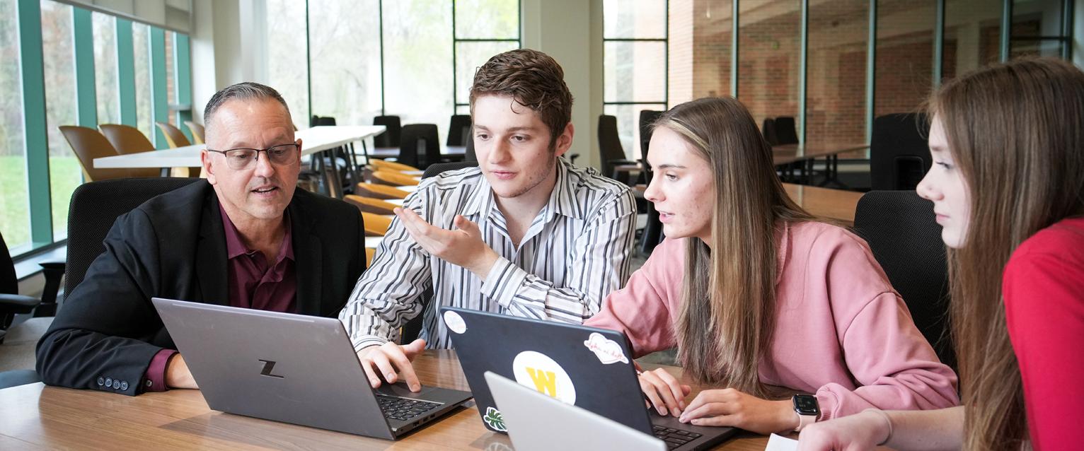 Financial Aid Reserouces, group of business students talking with a professor—Haworth Business College.